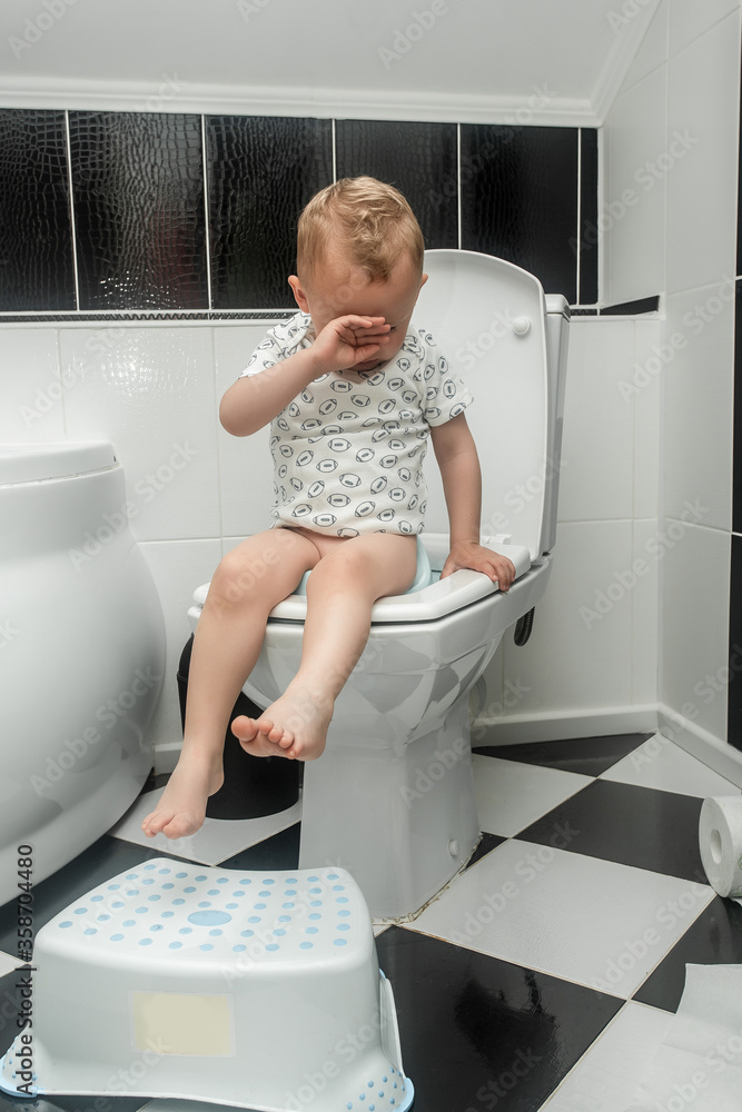 The child does not like to sit on the pot. Caucasian little boy with stomach ache