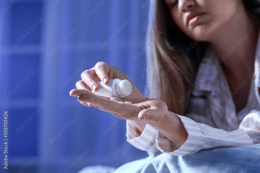 Young woman taking sleeping pills at night Young woman taking sleeping pills at night