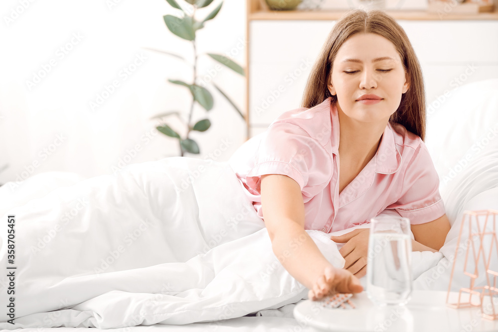 Young woman taking sleeping pills in bedroom Young woman taking sleeping pills in bedroom