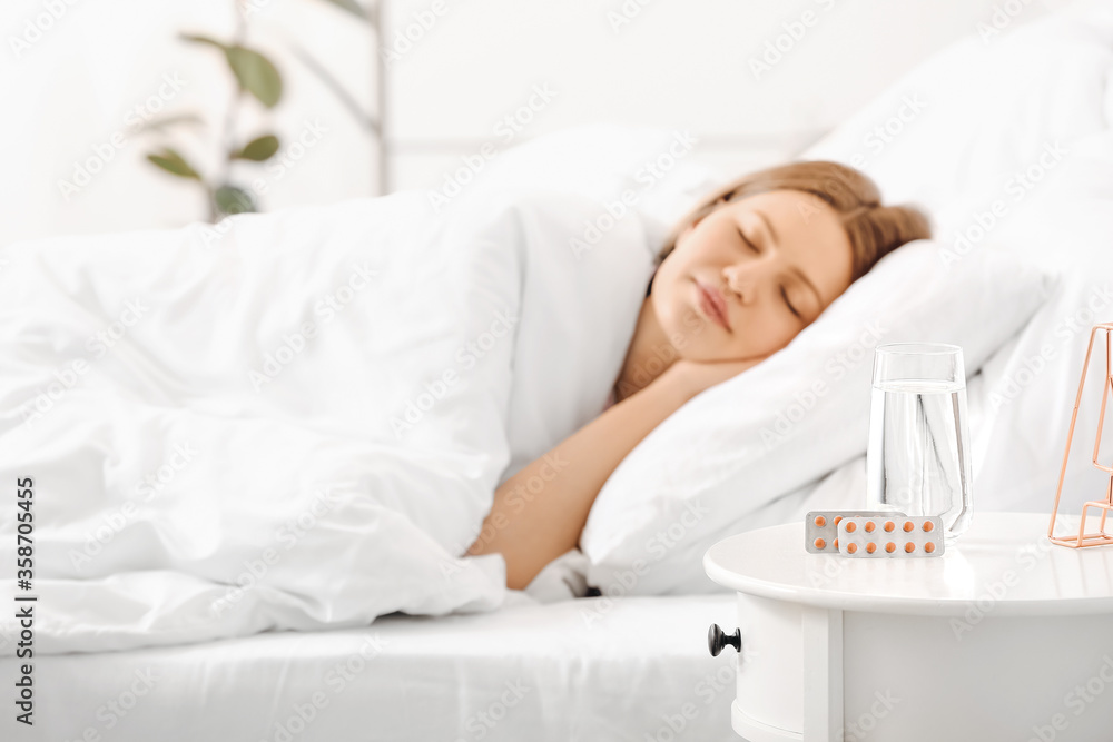 Sleeping pills on table in bedroom of young woman Sleeping pills on table in bedroom of young woman