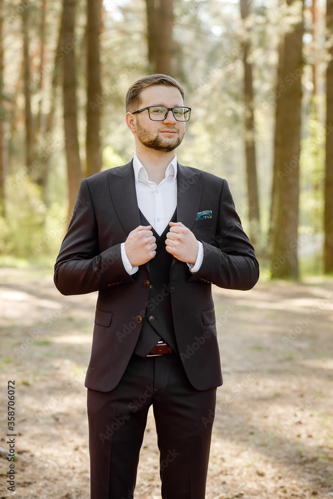 man in a dark suit posing in the forest. man in a dark suit posing in the forest.