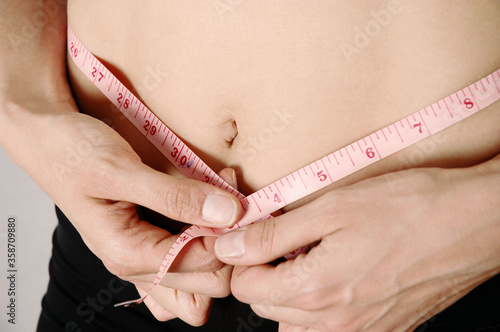 Woman measuring waist using tape measure