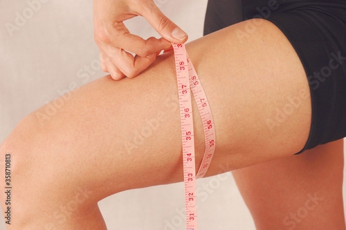 Woman measuring waist and leg using tape measure