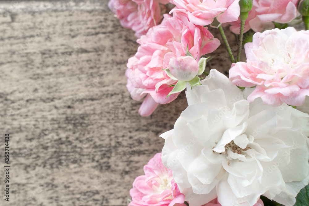 in the foreground on the right side are white and pink roses on a wooden table in the foreground on the right side are white and pink roses on a wooden table