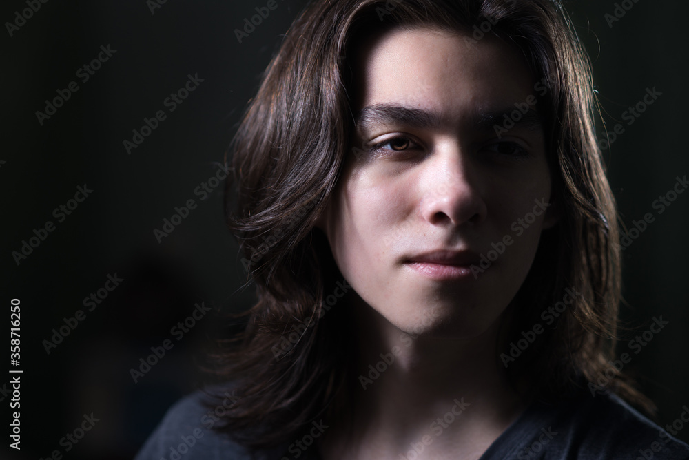 Portrait of young man with long hair in low key with Rembrandt lightning