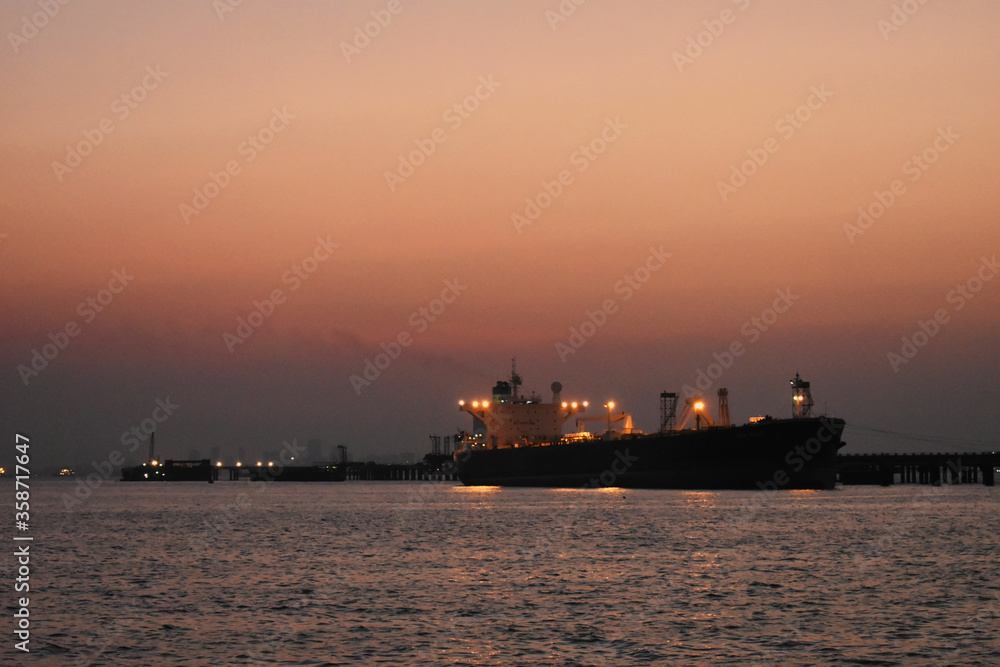 A merchant ship standing near the Port of Mumbai, captured in evening.