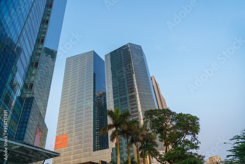 Closeup of top modern high-rise building in Kim Ma street, Hanoi, Vietnam. Mirroring of concrete skyscrapers on blue sky in shiny glass windows.