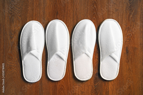 Top view of a pair white slippers in the hotel on wooden floor.
