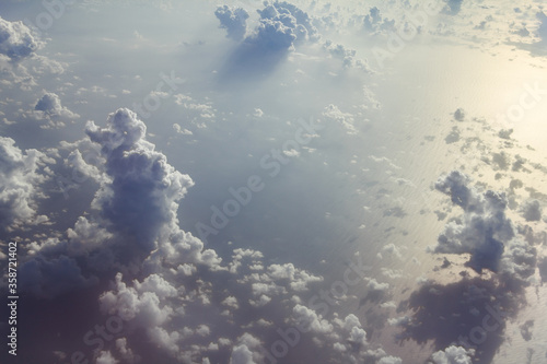 Blue sky with white clouds from the plane view.Cumulus clouds with interesting shadows.Beautiful amazing unusual multi-tiered clouds. Screensaver. Wallpaper. Background.