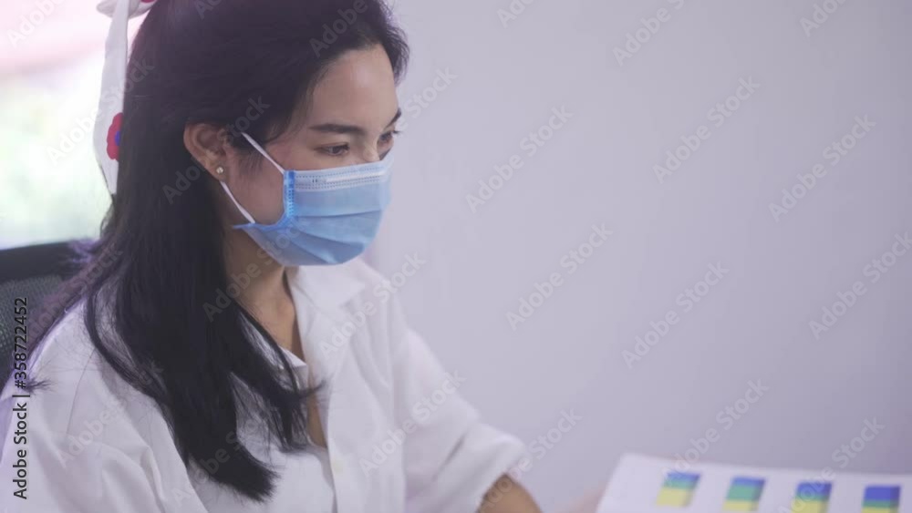 An Asian woman wears a mask while working at a computer desk. To prevent the disease of Covid 19 An Asian woman wears a mask while working at a computer desk. To prevent the disease of Covid 19