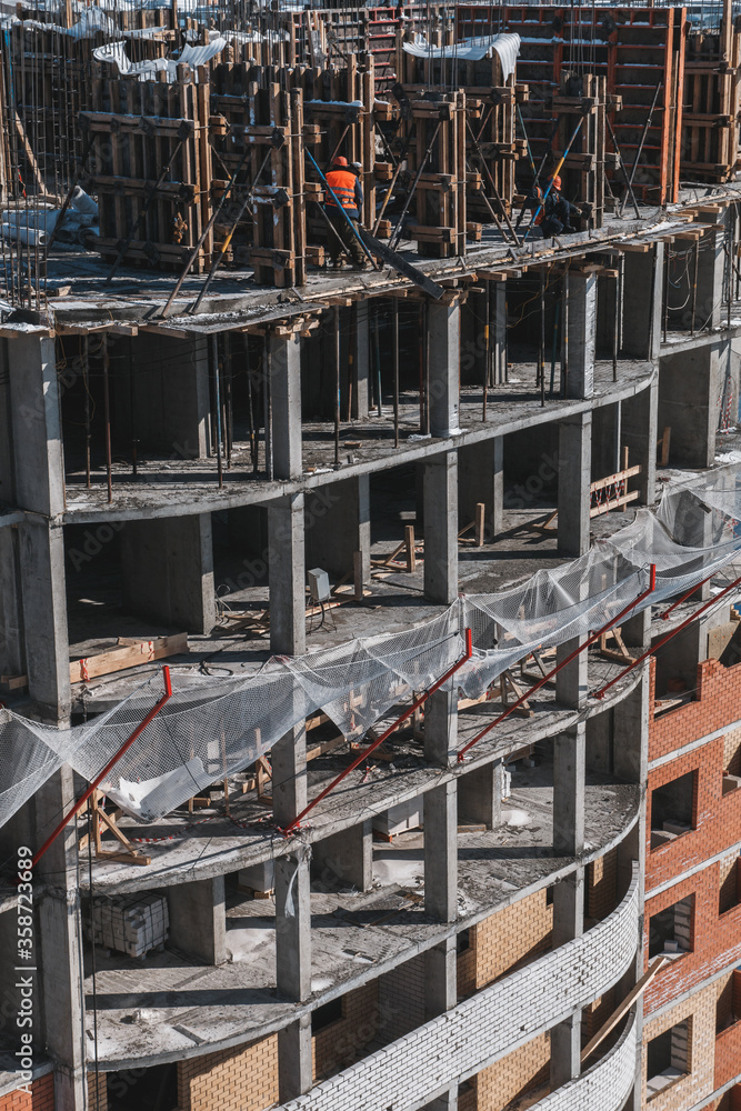 The course of construction of a multi-storey building. Ready-made floors, balconies, empty floors, mesh, fittings. Vertical orientation.