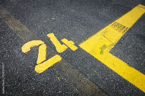 Number twenty-four yellow painted on the street, asphalt marks on cracked street, space for text, no people © YK