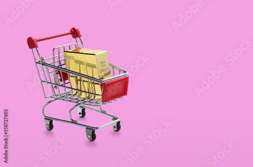 Shopping cart with gold bars on pink background.