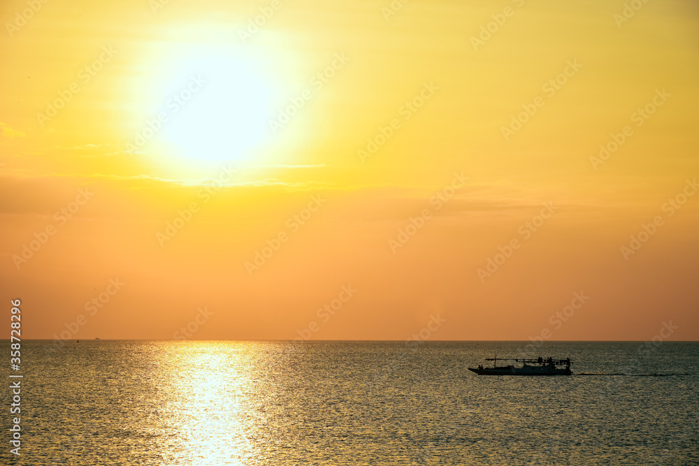 Silhouette of small fishing boat on the sea at sunset time
