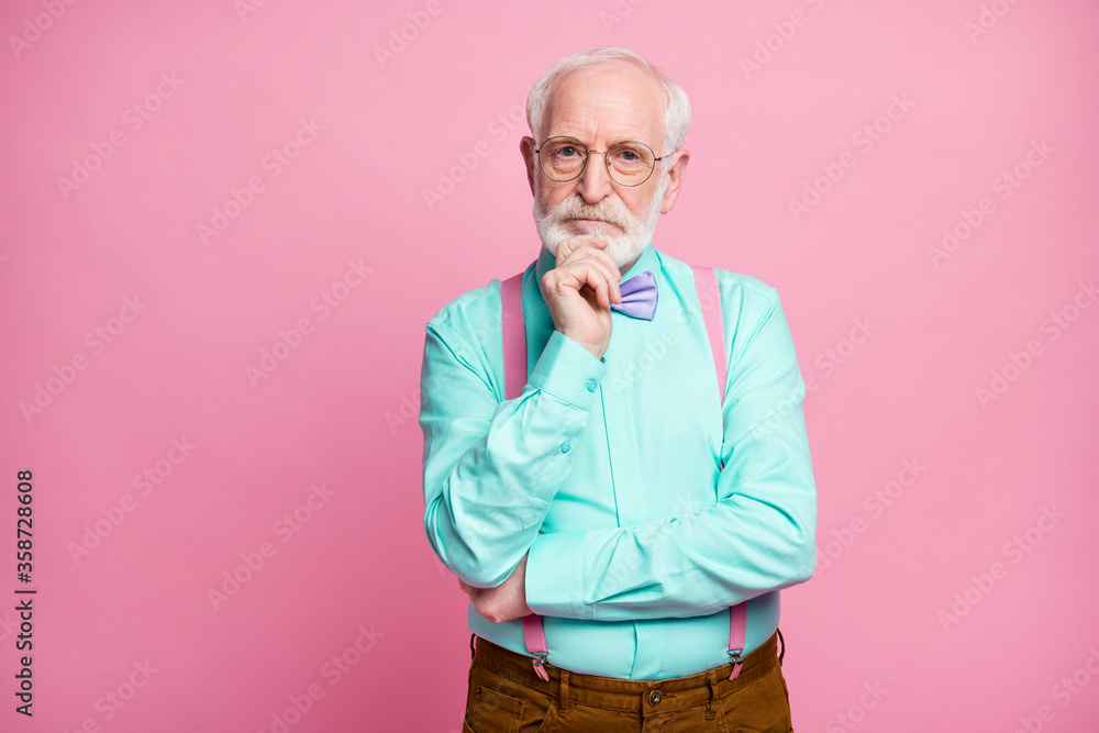 Photo of attractive stylish grandpa hold hand on chin look minded deep thinking not smiling wear specs mint shirt suspenders violet bow tie trousers isolated pink pastel color background Photo of attractive stylish grandpa hold hand on chin look minded deep thinking not smiling wear specs mint shirt suspenders violet bow tie trousers isolated pink pastel color background