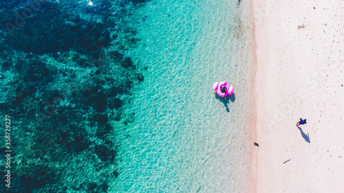 Aerial view of tourist floating on the beach with beautiful sea in Pink Beach, Labuan Bajo, Indonesia