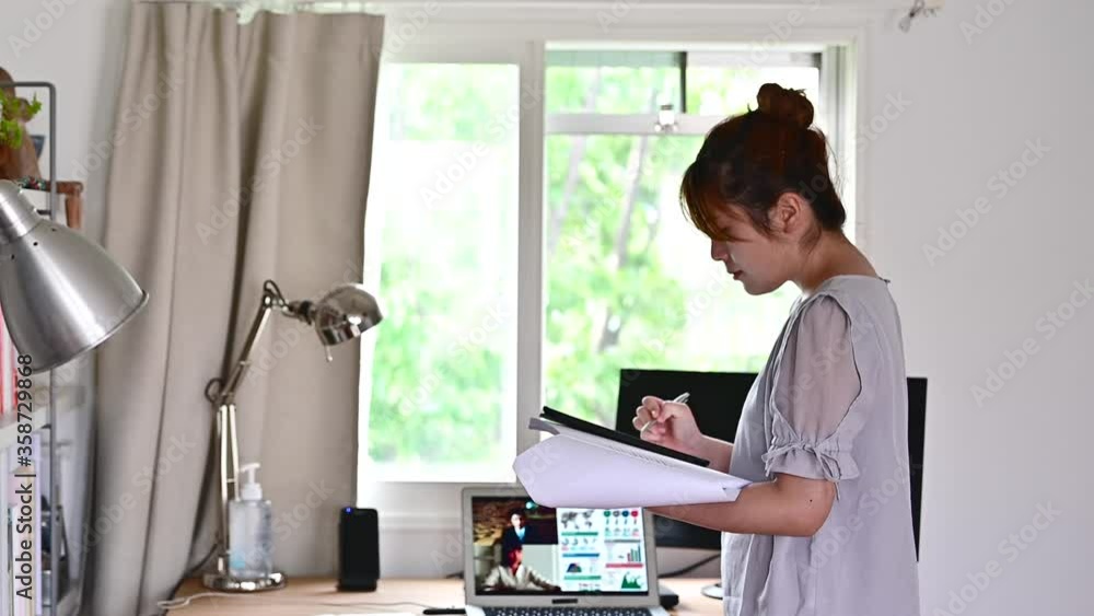 書斎のデスクで立ったまま仕事をする女性 書斎のデスクで立ったまま仕事をする女性
