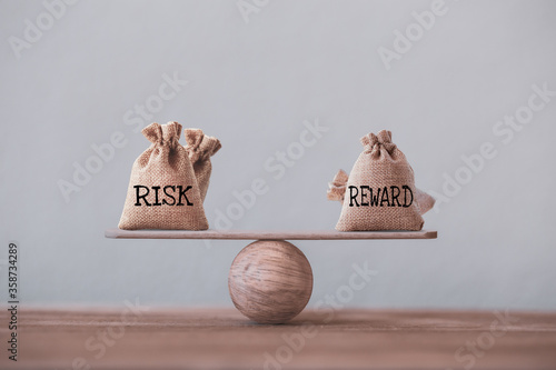 Risk and reward bags on a basic balance scale in equal position. risk management concept, depicts investors use a risk reward ratio to compare the expected return of an investment