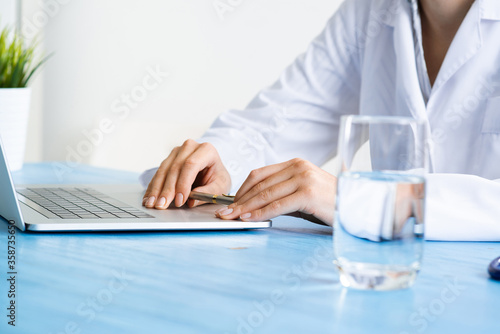 Close up of female doctor hands using laptop
