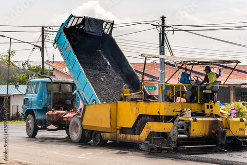 Kuching, Sarawak / Malaysia - September 22, 2018: Close up of lorry fills up asphalt onto a paver machine in a housing complex at daytime.