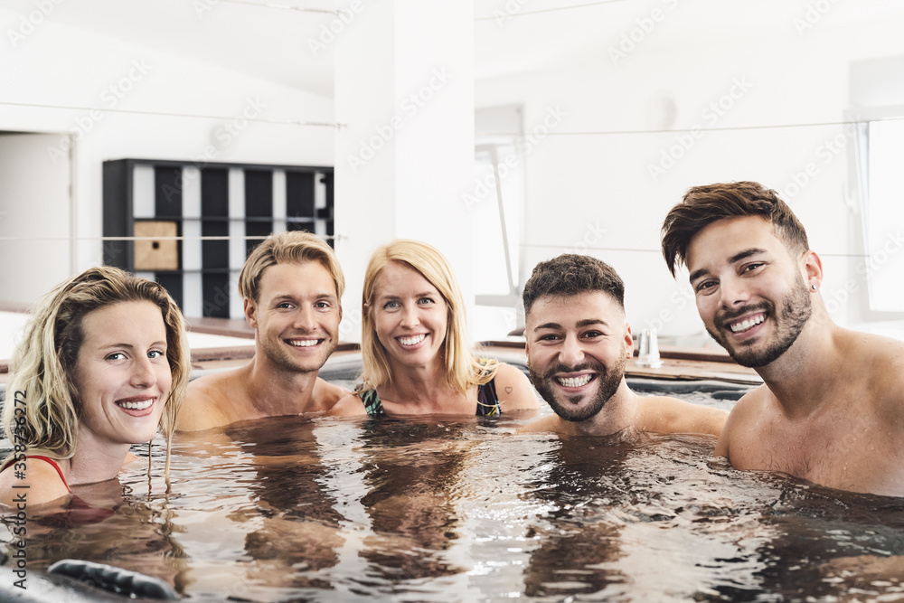 Happy friends enjoying vacations in jacuzzi luxury house - Young people having fun together in hot tub - Youth millennial generation and wellness lifestyle holidays