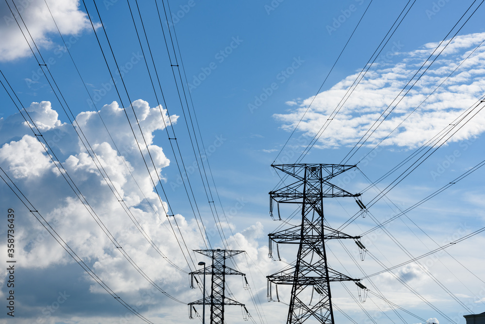 Kuching, Sarawak / Malaysia - August 28, 2017: Power poles and cables silhouetted in blue sky. Kuching, Sarawak / Malaysia - August 28, 2017: Power poles and cables silhouetted in blue sky.