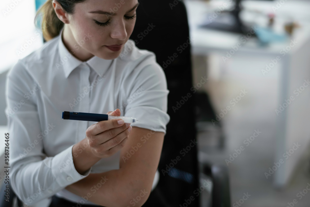 Businesswoman giving herself an injection of insulin.
Businesswoman giving herself an injection of insulin.