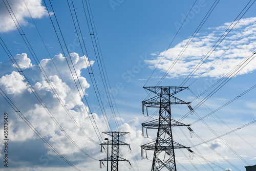 Kuching, Sarawak / Malaysia - August 28, 2017: Power poles and cables silhouetted in blue sky.