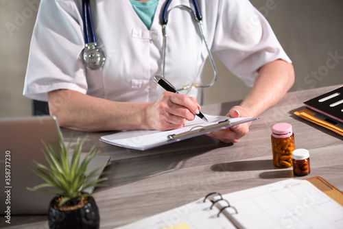 Female doctor taking notes on clipboard photo