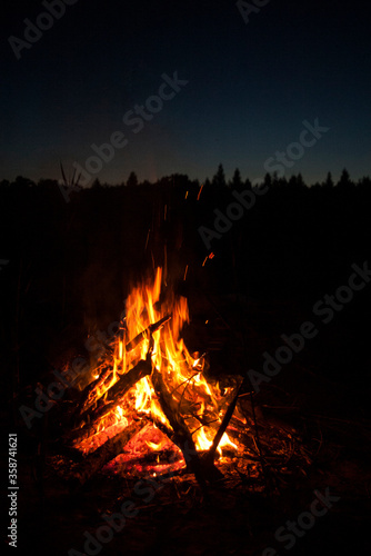 Warm bright bonfire / fireplace on the summer / spring night at the polish lake in the forest