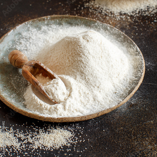 Raw fonio flour and seeds with a spoon on dark background