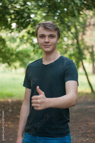 Fototapeta Naklejka Na Ścianę i Meble -  Happy young man gives a thumbs up and looks at the camera