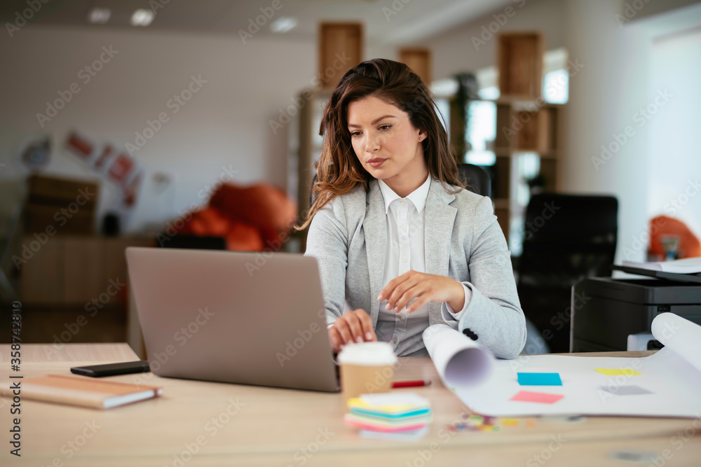 Beautiful young businesswoman working on project. Businesswoman in suit working in office.	