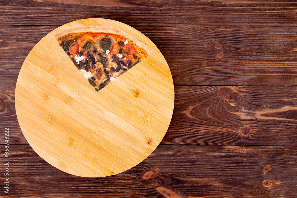Quarter of pizza with cherry tomatoes, spinach, mozzarella, feta, kalamata olive and mushrooms on round wood plate which is on wooden rustic background, top view and space for your text Quarter of pizza with cherry tomatoes, spinach, mozzarella, feta, kalamata olive and mushrooms on round wood plate which is on wooden rustic background, top view and space for your text
