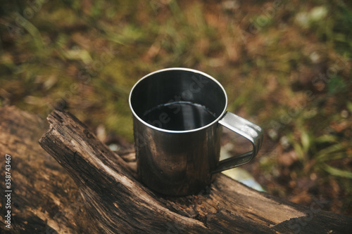 Travel titanium cup on wood. Camping lifestyle.