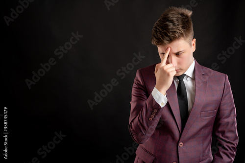 Law student with blond hair dressed in burgundy jacket, white shirt and black tie wondering