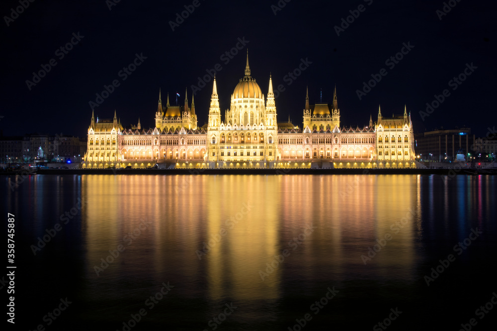 Fototapeta premium Hungarian Parliament building and Danube River in the Budapest city at night. A sample of neo-gothic architecture, Budapest's tourist attraction