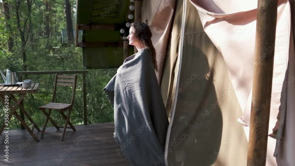 girl wrapped in a plaid on the balcony in a mountain house. Attractive brunette girl enjoys nature in the mountains on the balcony, covered with a plaid girl wrapped in a plaid on the balcony in a mountain house. Attractive brunette girl enjoys nature in the mountains on the balcony, covered with a plaid