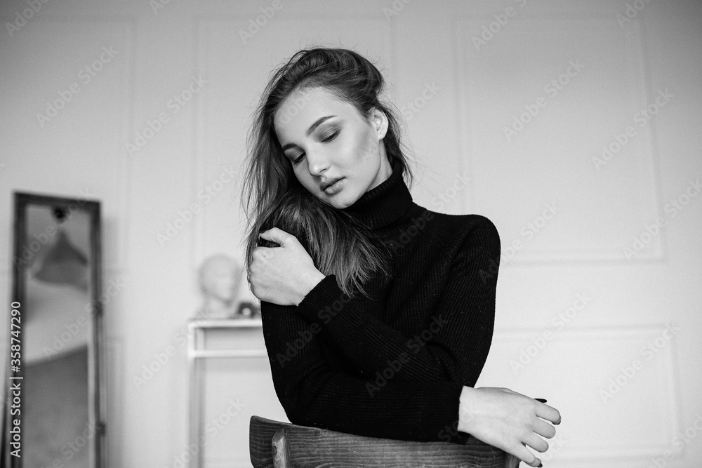 girl woman model sitting on a chair in a stylish room white in brown trousers girl woman model sitting on a chair in a stylish room white in brown trousers