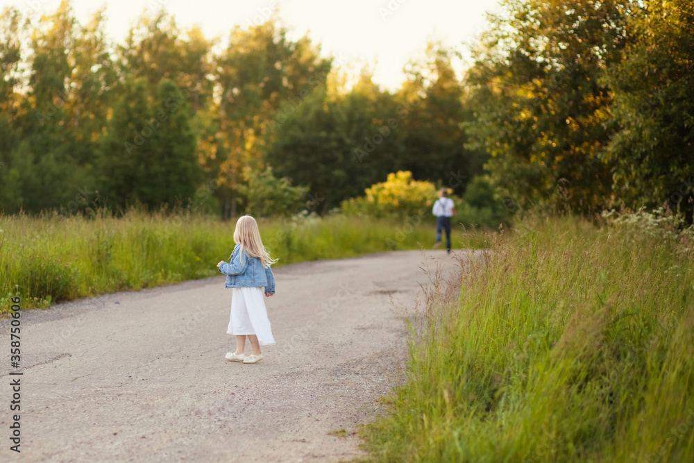 Fototapeta premium Children girl and boy siblings running on the road. Back view. The concept of summer, childhood, freedom, fun outdoors. Soft focus.