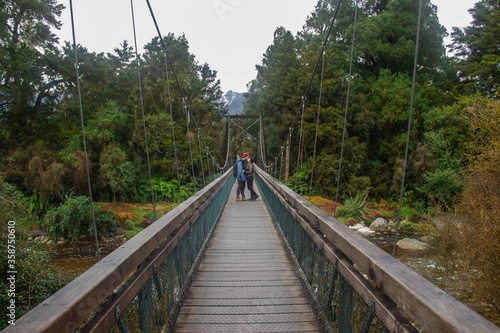 Couple over the bridge on the track on the way to Lake Matheson. New Zealand South Island. June    12     2018