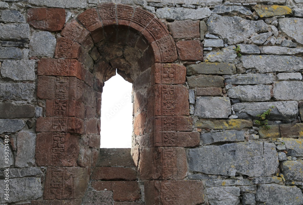 A decoratively carved arched window in a ruined church.