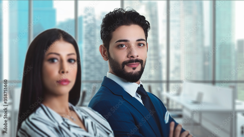 Concept of partnership in business. Young man and woman standing side to side with crossed hands against modern office background Concept of partnership in business. Young man and woman standing side to side with crossed hands against modern office background
