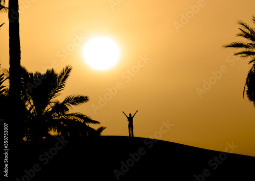 chica con brazos abiertos en una duna al atardecer en el desierto