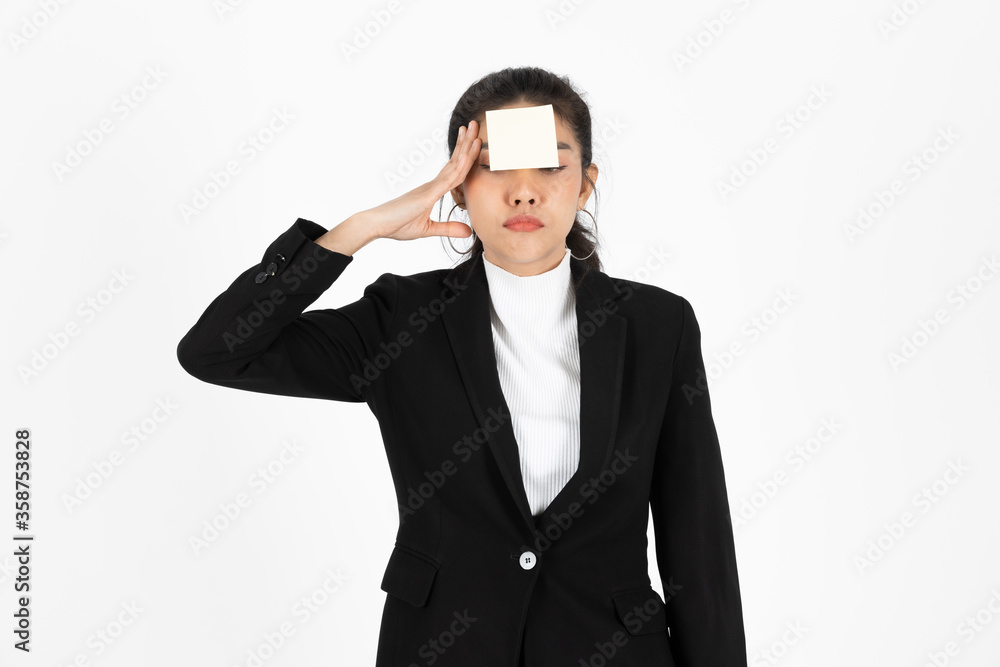 Exhausted tired young Asian business woman in formal wear with adhesive note on her forehead over white isolated background.