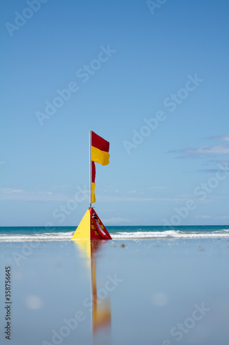 A swimming flag on a beach in the middle of summer. 