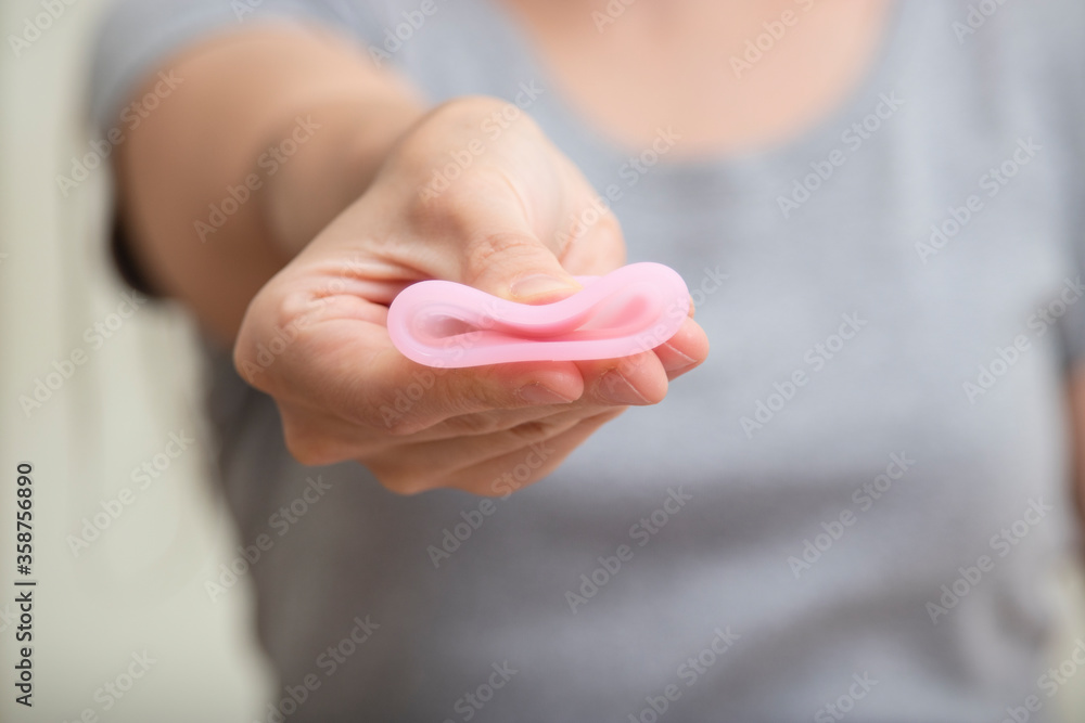 Close up of woman hand folding menstrual cup showing how to use. Women health concept, zero waste alternatives Close up of woman hand folding menstrual cup showing how to use. Women health concept, zero waste alternatives