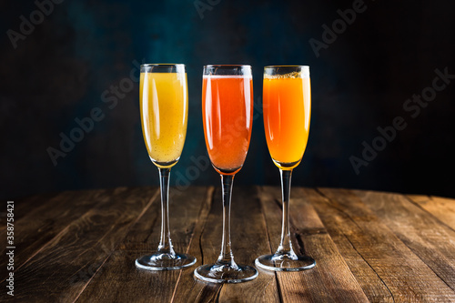 Three different sparkling fruity cocktails, red, yellow and orange, in flute glasses
