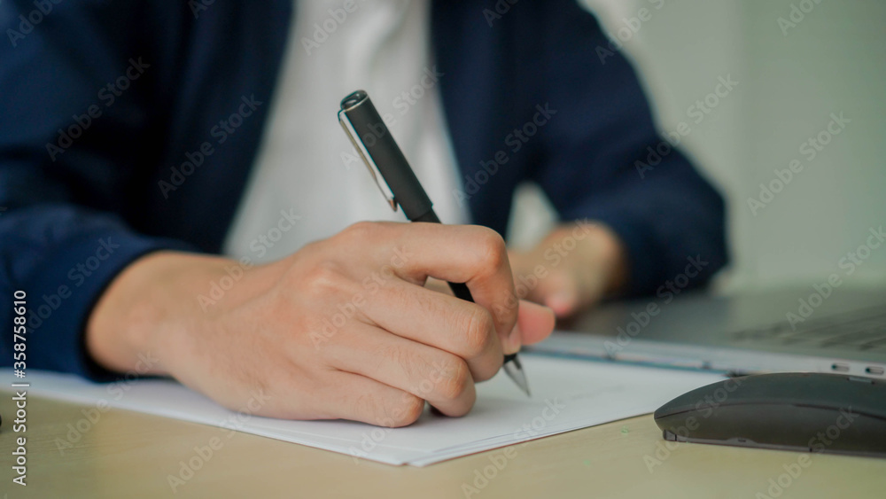 close up businessman hand using ball-point pen to writing about list of work from online webinar meeting for work from home concept close up businessman hand using ball-point pen to writing about list of work from online webinar meeting for work from home concept