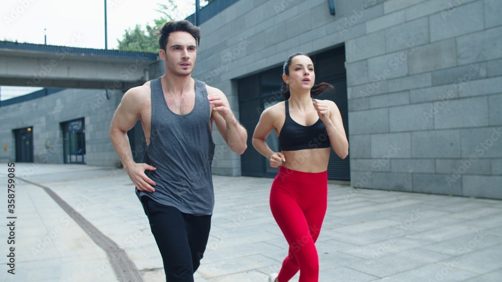 Fitness couple running on urban street together. Sporty family training run Fitness couple running on urban street together. Sporty family training run